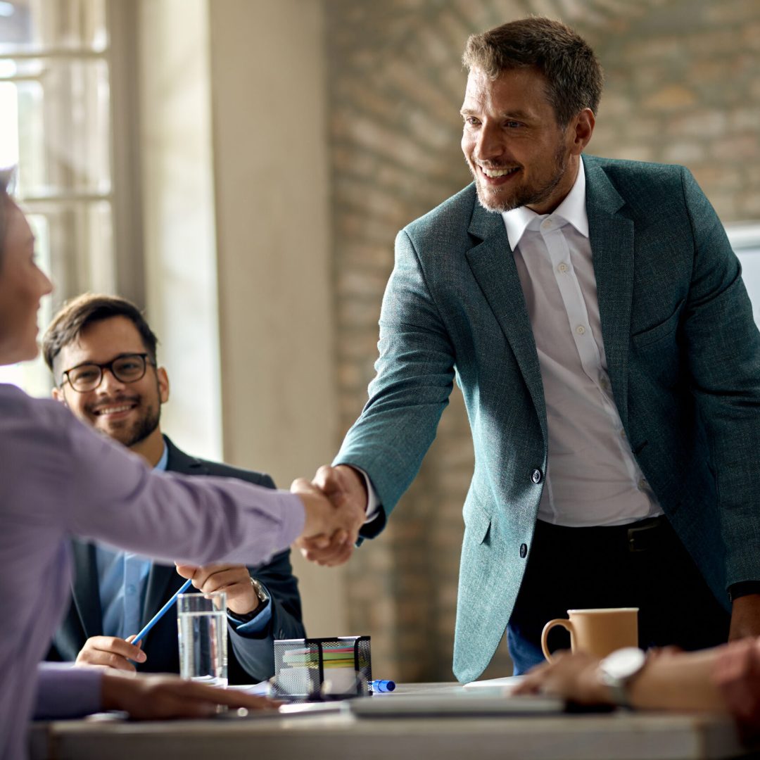 Business coworkers shaking hands during a meeting in the office. Focus is on a businessman.